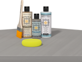 Retique It® Weathered Wood Multipurpose Kit contents with Light Wood Liquid Wood primer, Weathered Wood gel stain alternative, Tripletique matte interior top coat, paintbrush, and yellow sponge displayed on a wood surface.