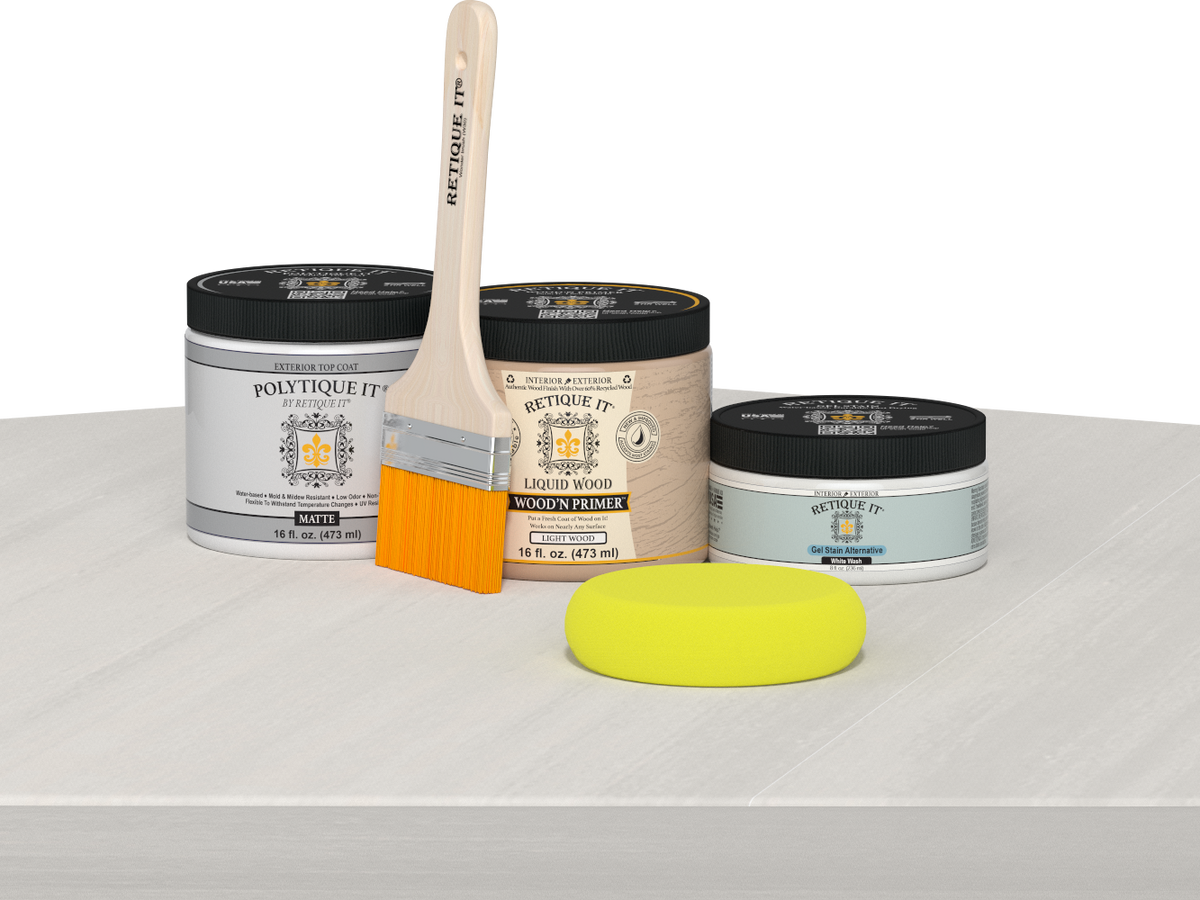 Retique It® White Wash Multipurpose Kit contents with Liquid Wood primer, White Wash gel stain alternative, PolyTique It® matte exterior top coat, paintbrush, and yellow sponge displayed on a white wood surface.