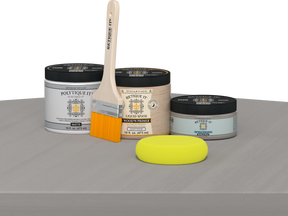 Retique It® Weathered Wood Multipurpose Kit contents with Light Wood Liquid Wood primer, Weathered Wood gel stain alternative, PolyTique It® matte exterior top coat, paintbrush, and yellow sponge displayed on a gray wood surface.