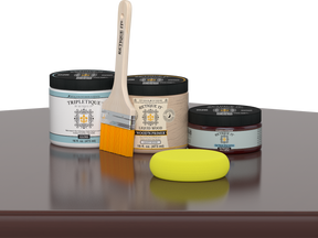 Retique It® Red Mahogany Multipurpose Kit contents with Liquid Wood primer, Red Mahogany gel stain alternative, Tripletique gloss interior top coat, paintbrush, and yellow sponge displayed on a dark wood surface.