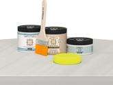 Retique It® White Wash Multipurpose Kit contents with Liquid Wood primer, White Wash gel stain alternative, Tripletique matte interior top coat, paintbrush, and yellow sponge displayed on a white wood surface.