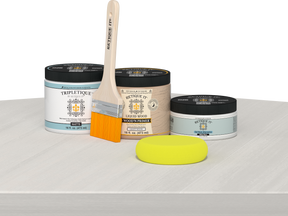 Retique It® White Wash Multipurpose Kit contents with Liquid Wood primer, White Wash gel stain alternative, Tripletique matte interior top coat, paintbrush, and yellow sponge displayed on a white wood surface.