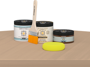 Retique It® Pecan Multipurpose Kit contents with Bleached Wood Liquid Wood primer, Pecan gel stain alternative, Tripletique matte interior top coat, paintbrush, and yellow sponge displayed on a light wood surface.