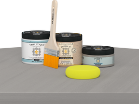 Retique It® Weathered Wood Multipurpose Kit contents with Light Wood Liquid Wood primer, Weathered Wood gel stain alternative, Tripletique matte interior top coat, paintbrush, and yellow sponge displayed on a gray wood surface.