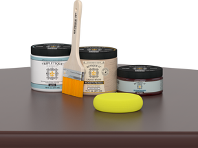Retique It® Red Mahogany Multipurpose Kit contents with Liquid Wood primer, Red Mahogany gel stain alternative, Tripletique satin interior top coat, paintbrush, and yellow sponge displayed on a dark wood surface.