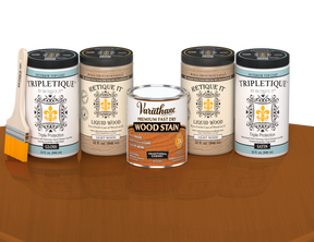 64 oz Retique It Liquid Wood kit with Traditional Cherry stain, gloss Tripletique topcoat, and a paintbrush on a matching finished tabletop.