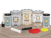Sun-bleached Retique It Wood'n Finish Kit with four large exterior top coat containers on a table, matte finish for wood projects.